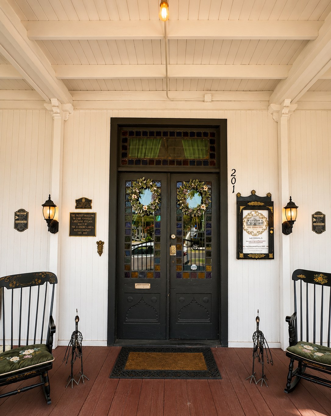 The charcoal double-door entry of The Crescent House, framed by a checkered stained-glass transom and a historic register plaque