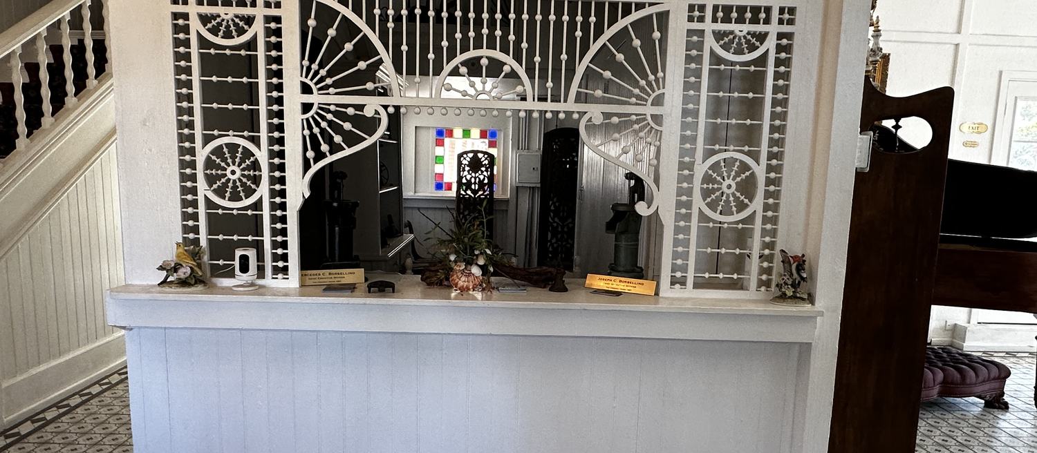 The original 1887 lobby screen at The Crescent House, a white spindle-and-ball fretwork partition with sunburst wheels